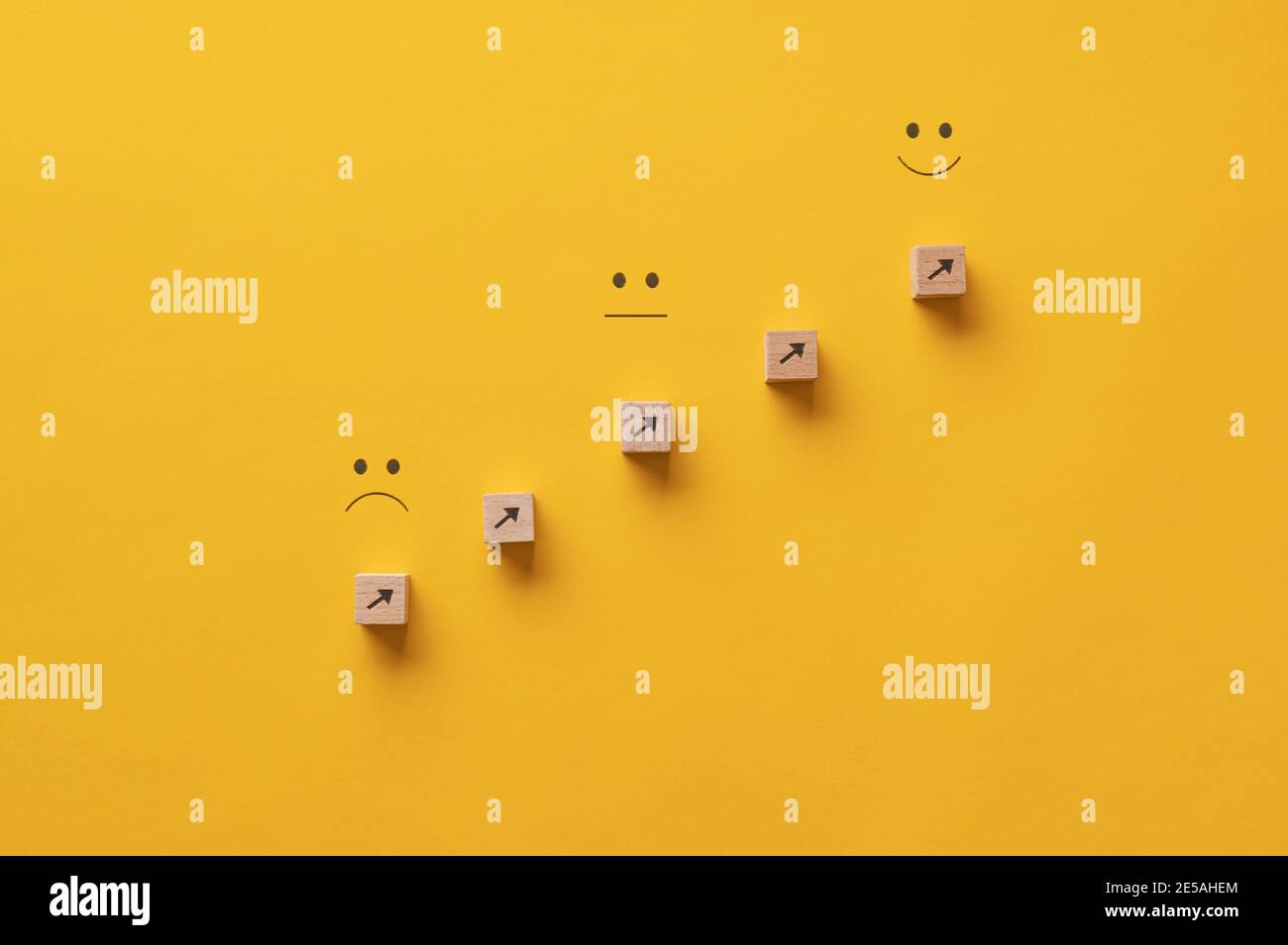 Pfeile, die von einem traurigen Ausdruck auf einen glücklichen zeigen - konzeptuelles Bild von persönlichem Wachstum und Streben. Stockfoto