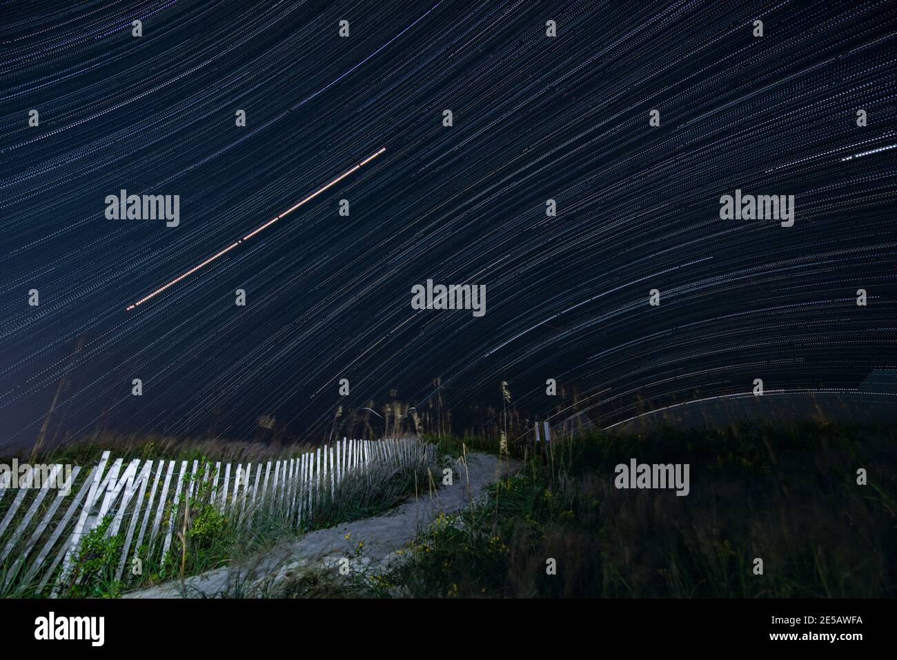 Eine lange Belichtung zeigt den Weg der Sterne am Himmel über Atlantic Beach, North Carolina. Stockfoto