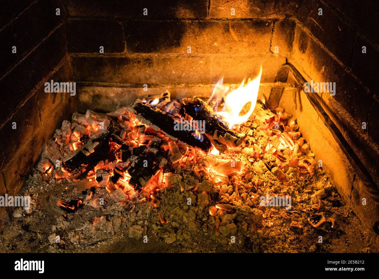 Schwelendes Feuerholz und heiße Asche im Kamin Stockfoto