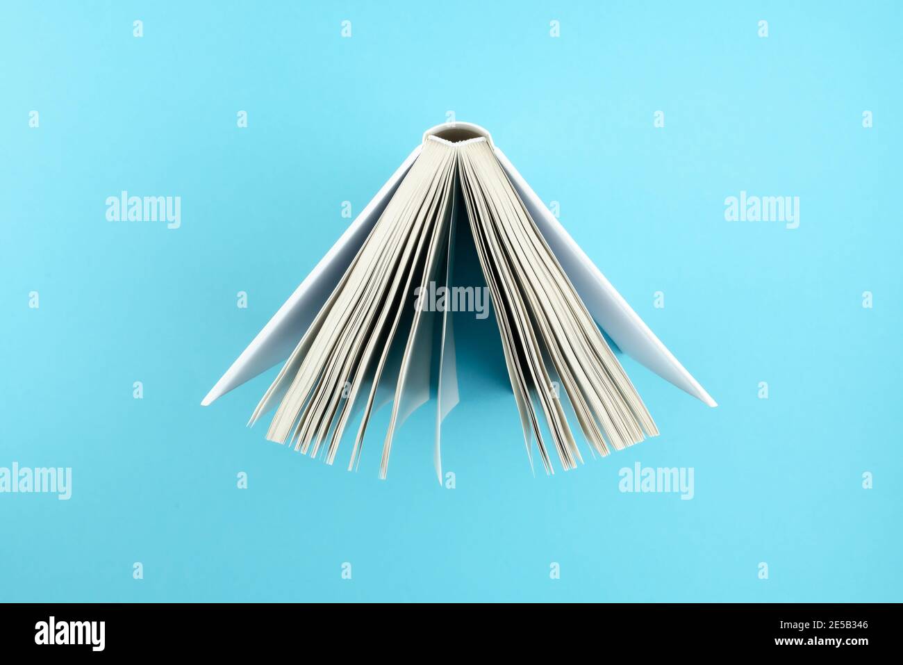 Direkt über Ansicht der Oberseite des offenen Hardcover Buches auf Blauer Hintergrund Stockfoto
