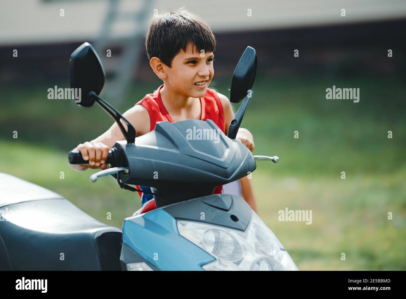 Ein Junge fährt einen Roller oder ein kleines Fahrrad. Das Kind ist für das Führen eines Fahrzeugs verantwortlich. Stockfoto