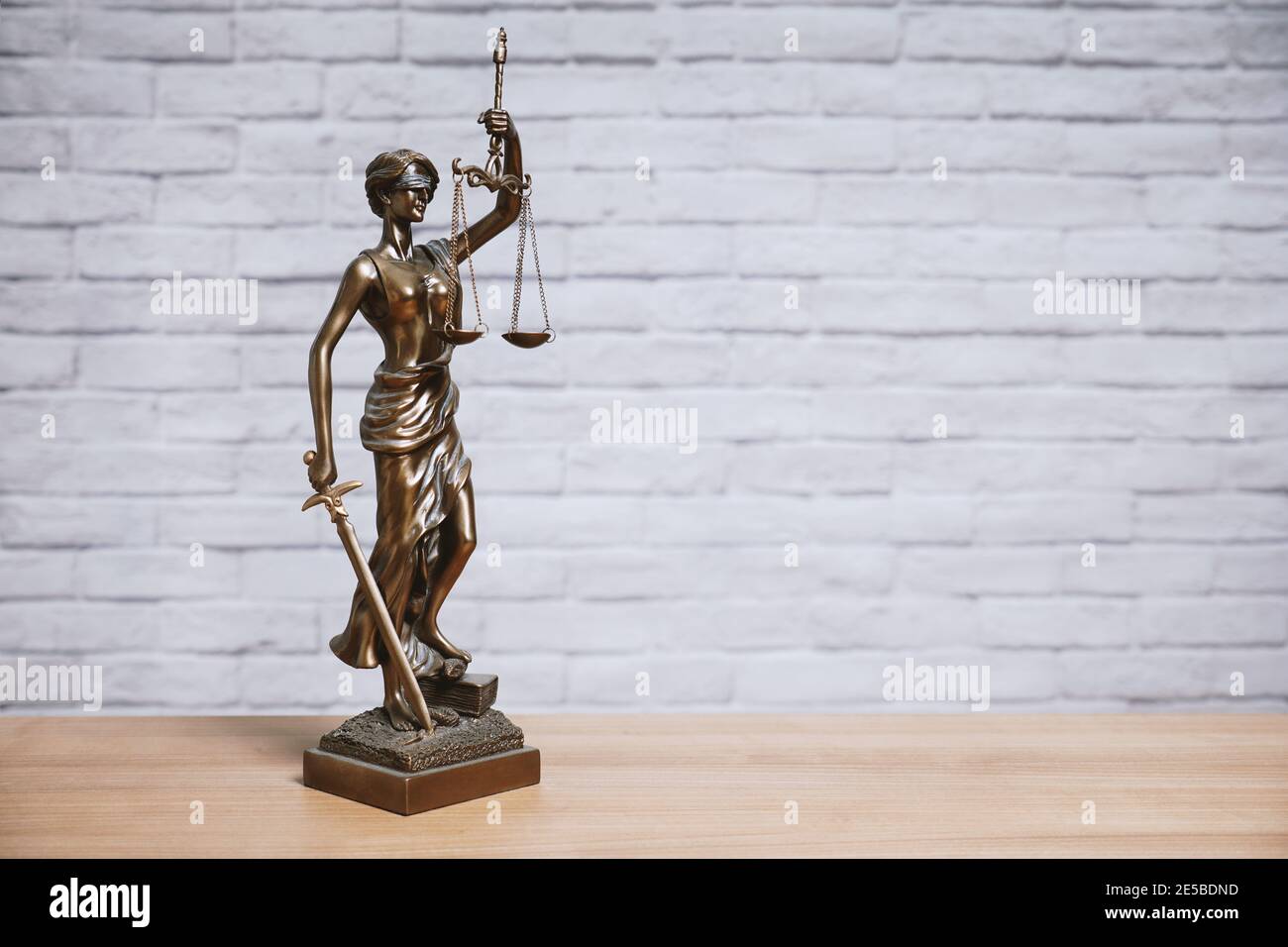 Lady Justice oder Justitia die Göttin der Gerechtigkeit Statue auf Schreibtisch - Rechtsgesetzgebung Konzept - Backsteinwand Hintergrund Mit Kopierbereich Stockfoto