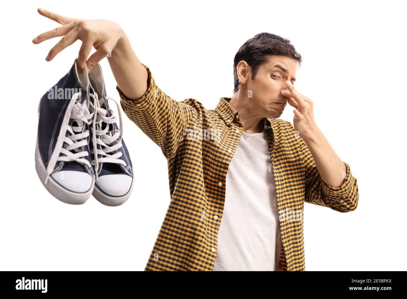 Kerl hält ein Paar riechende Trainer isoliert auf weiß Hintergrund Stockfoto