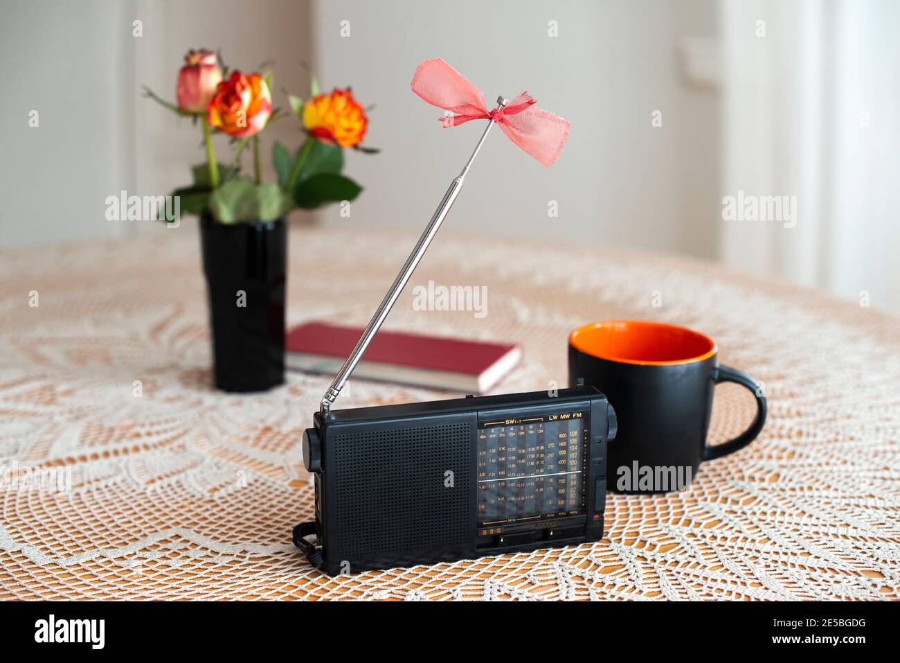 Stillleben mit Retro-Radio-Empfänger, Blumen, Kaffeetasse und Buch. World Radio Day. Stockfoto