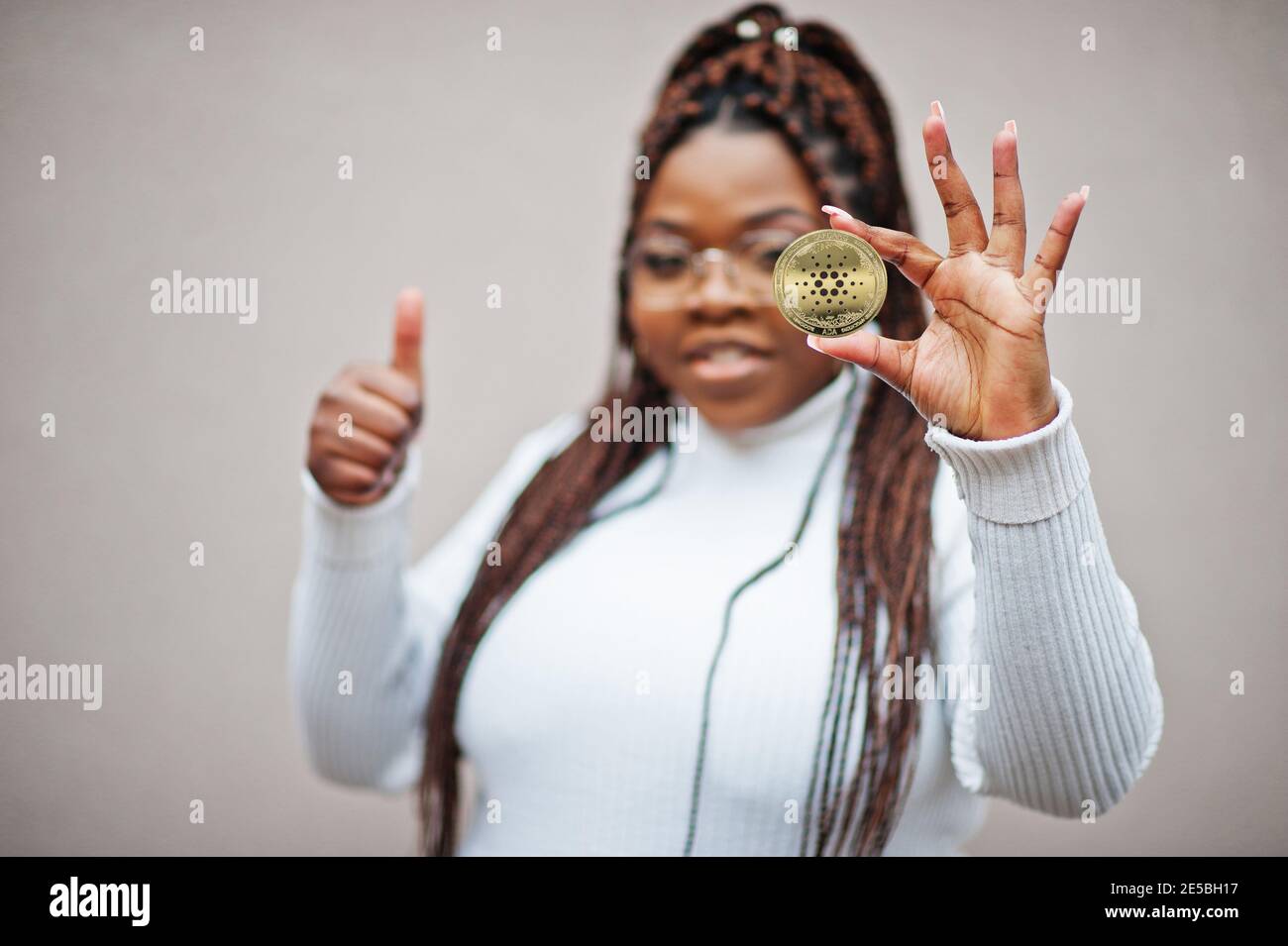 afroamerikanische Geschäftsfrau zeigen Cardano Münze und Daumen hoch. Kryptowährung Konzept. Stockfoto