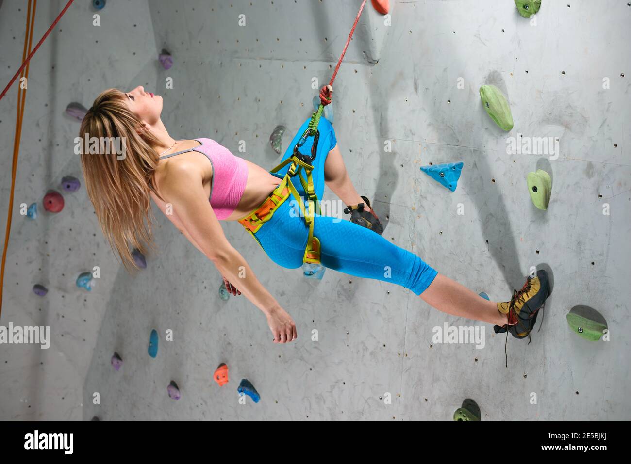 Junge Klettererin beim Entspannen auf dem Belay in der Kletterhalle. Extreme Sport und Indoor Climbing Konzept Stockfoto