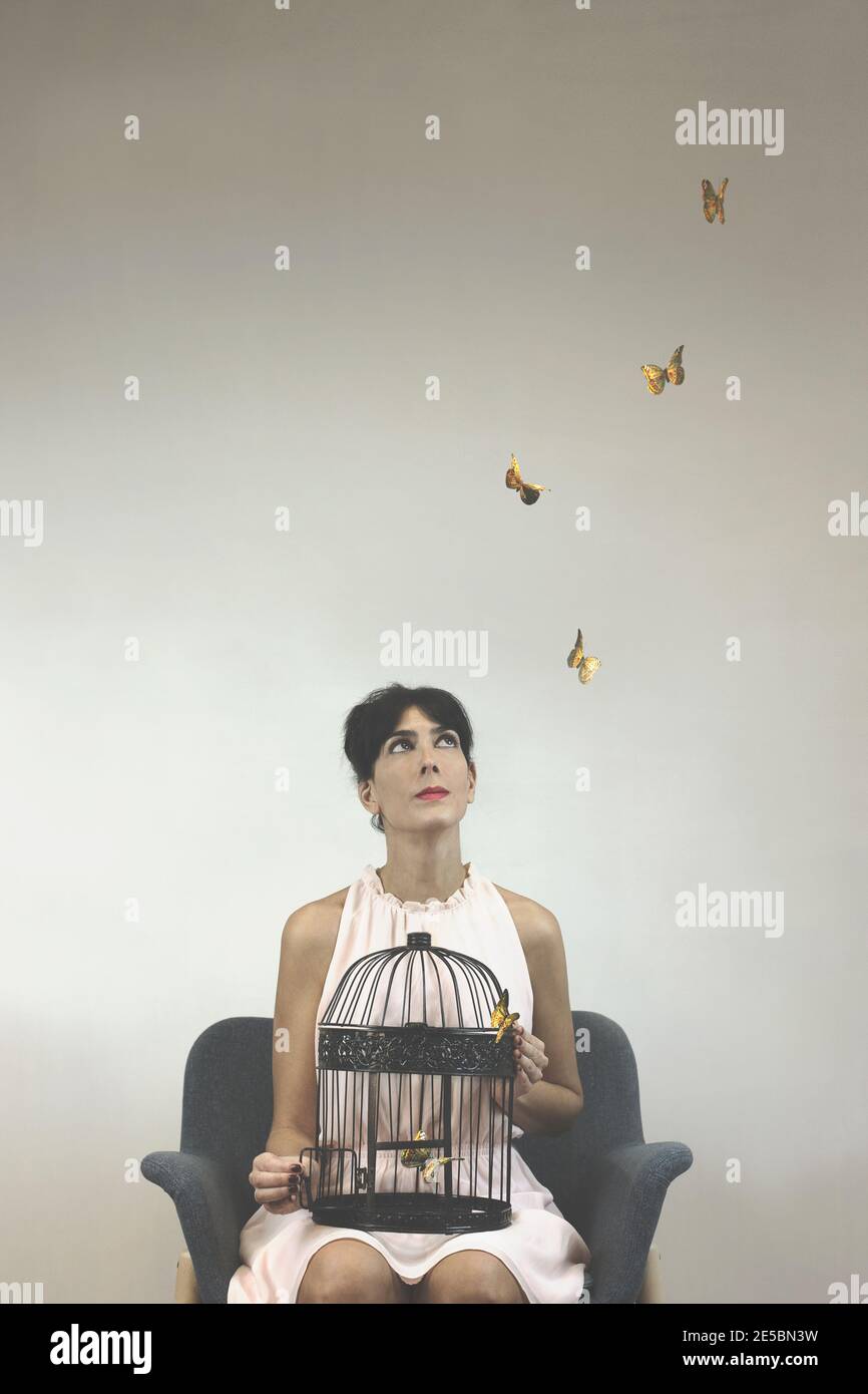 Konzeptuelles Foto der Freiheit mit einer Frau, die bunte Kunst veröffentlicht Schmetterlinge aus einem Käfig Stockfoto