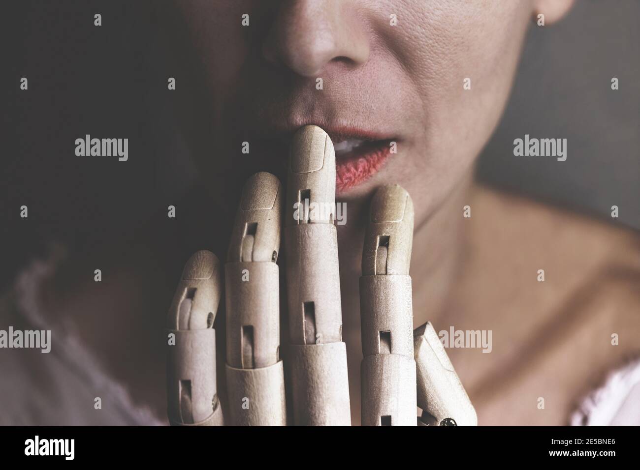 Surrealer Moment einer hölzernen Hand, die den Mund einer Frau berührt Stockfoto