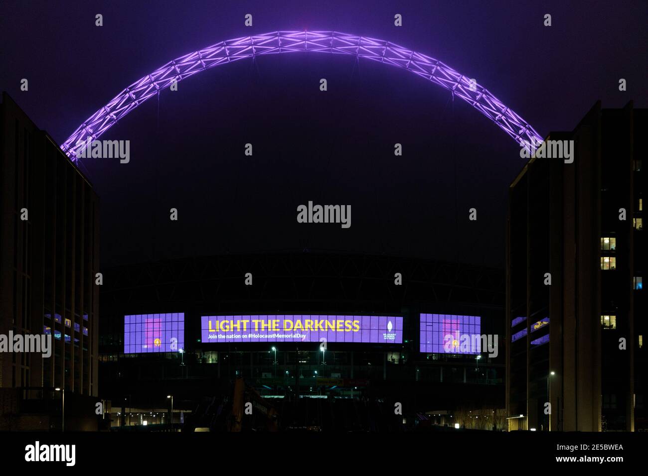 Wembley Stadium, Wembley Park, Großbritannien. Januar 2021. Anlässlich des Holocaust-Gedenktages zeigt das Wembley-Stadion die Botschaft des Gedenkens an die Opfer der Shoah. "Light the Darkness", während der ikonische Bogen ist lila beleuchtet zusammen mit 25 anderen Standorten in ganz Großbritannien. Amanda Rose/Alamy Live News Stockfoto