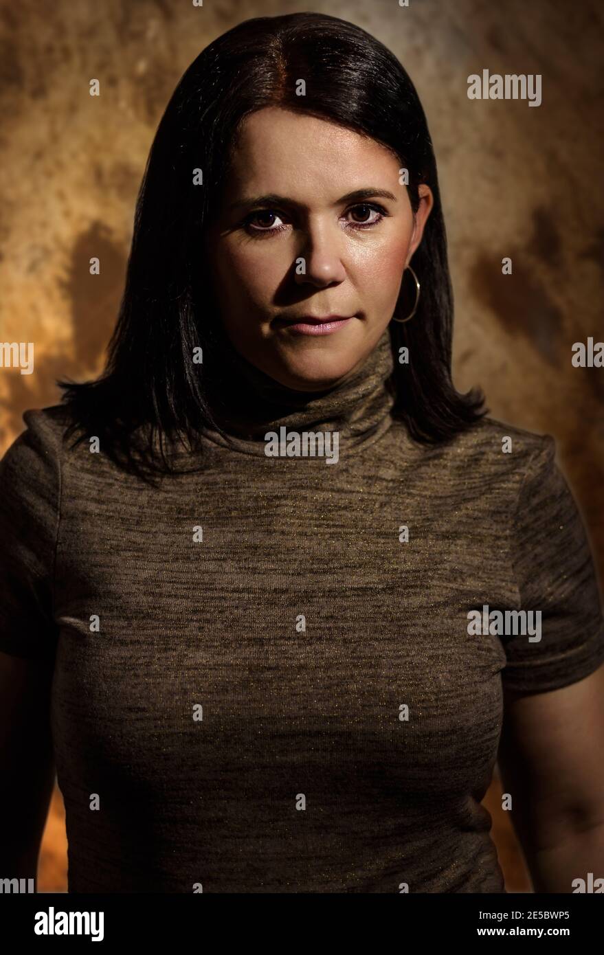 Dramatische Porträt einer ernst aussehenden Brunete kaukasischen Geschäftsfrau trägt Rollkragen Bluse mit kurzen Ärmeln. Blick auf die Kamera Low Key po Stockfoto