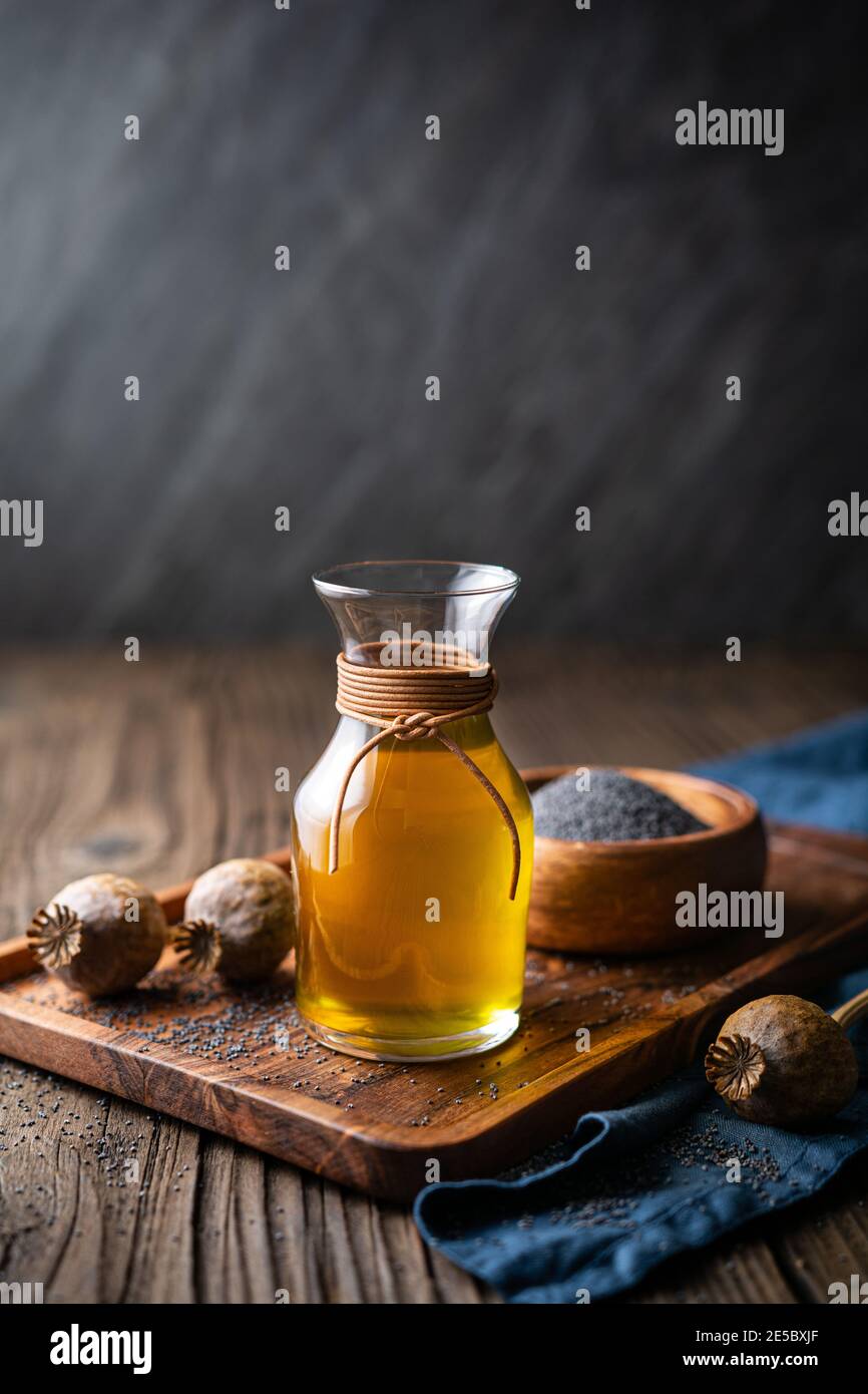 Bio kaltgepresstes Mohn-Samenöl in einer Glaskaraffe Auf einem hölzernen Hintergrund Stockfoto