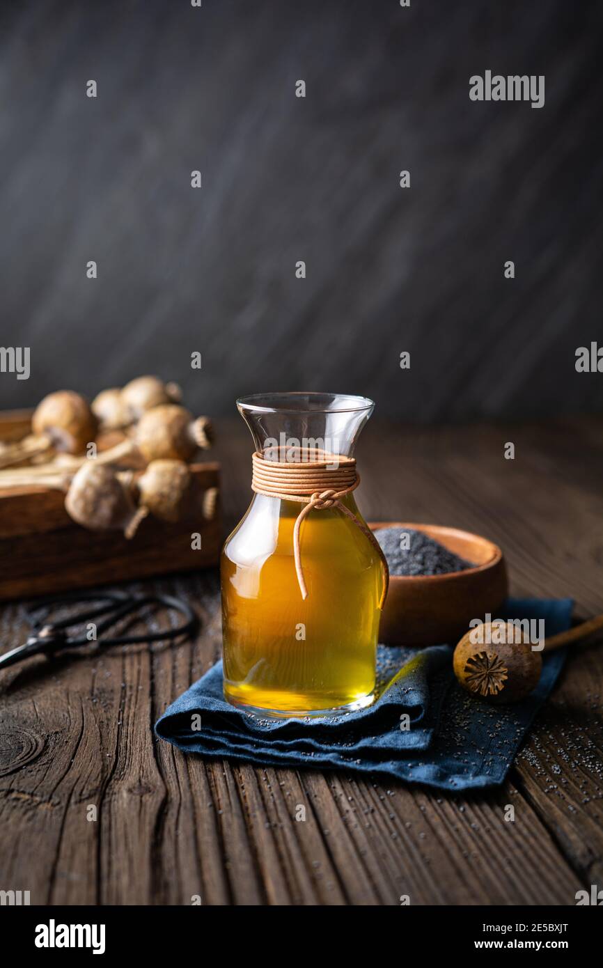 Bio kaltgepresstes Mohn-Samenöl in einer Glaskaraffe Auf einem hölzernen Hintergrund Stockfoto