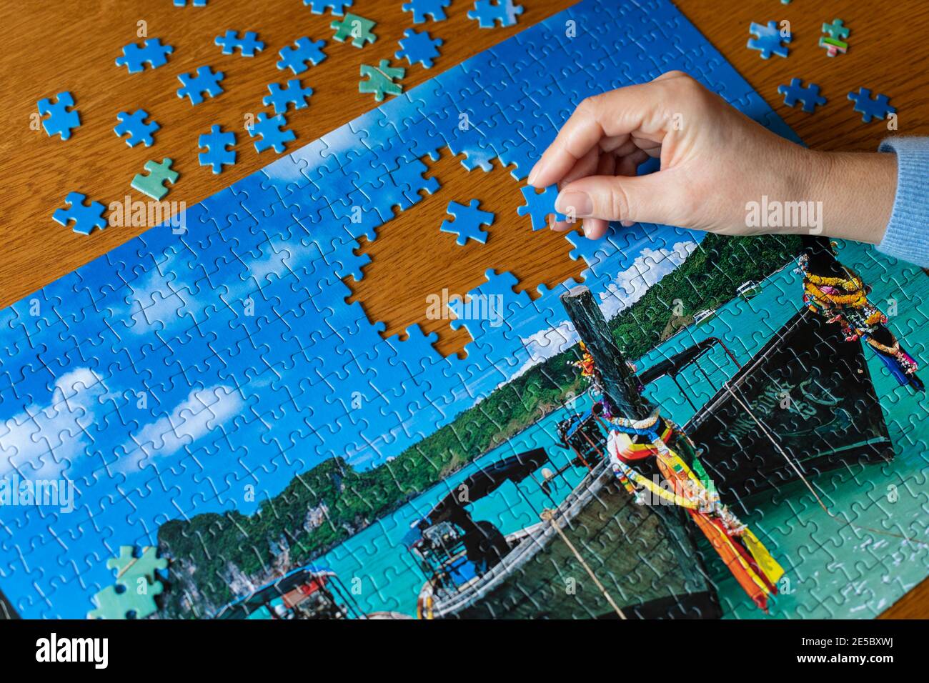 Hand der Frau mittleren Alters Abschluss ein Puzzle von Longtail Boote in Thailand Stockfoto