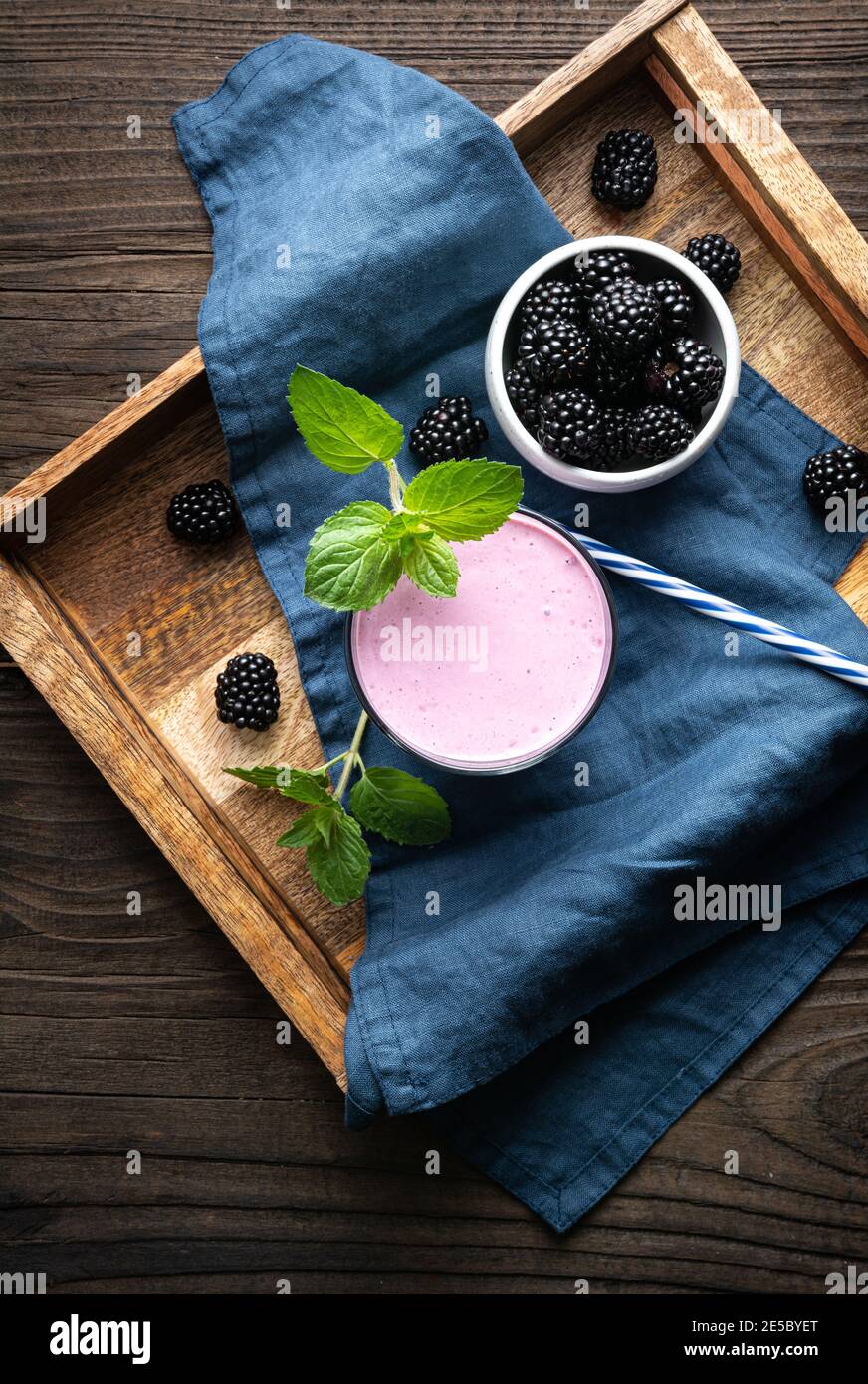 Süßes Milchgetränk, Brombeermilchshake im Glas auf Holzgrund Stockfoto