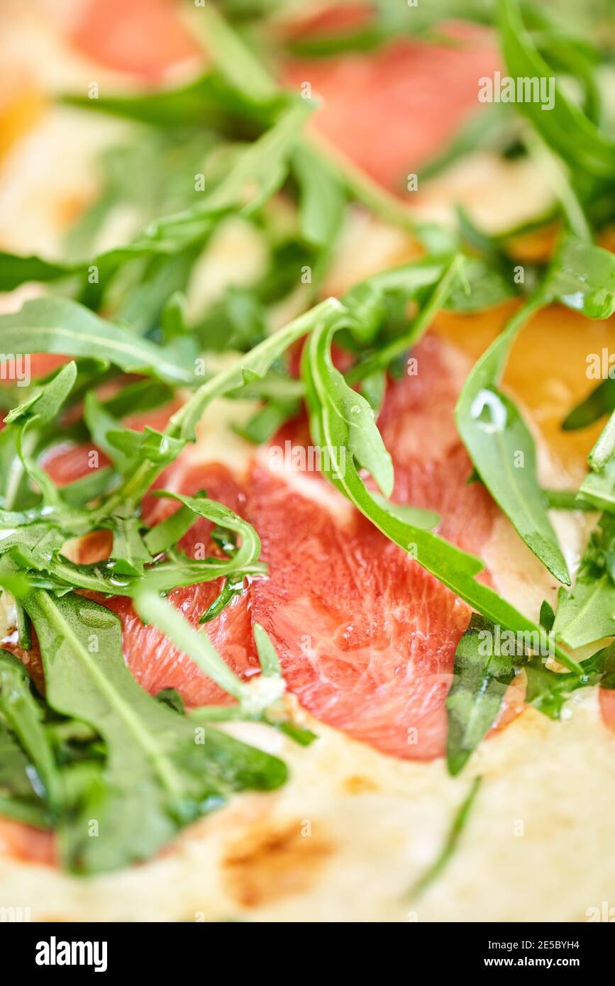 Italienische Pizza mit Ente aus dem Holzofen. Mittagessen in einem italienischen Restaurant. Tisch in der Nähe eines großen Fensters. Stockfoto