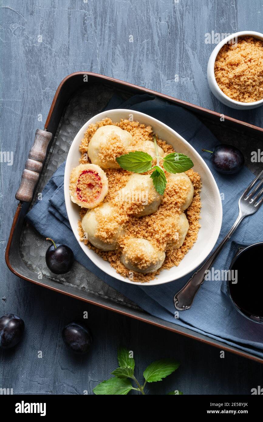 Frisch gekochte Pflaumenknödel garniert mit süßen gerösteten Paniermehl in einer Schüssel, serviert mit schwarzem Johannisbeersaft Stockfoto