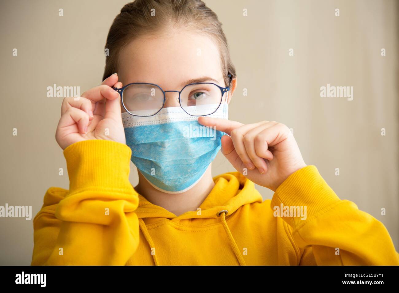 Neblige Brille trägt auf junge Frau. Teenager-Mädchen in medizinischen Schutz Gesichtsmaske und Brillen wischt verschwommen neblig vernebelte Gläser. Neuer Normalwert fällig Stockfoto