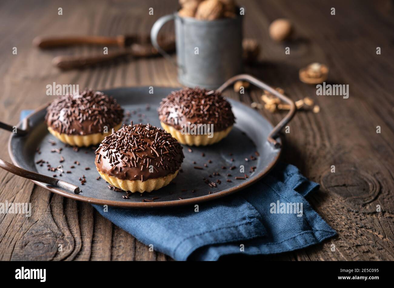 Frisch zubereitete süße Linzer Keksbecher mit Walnussfüllung, gekrönt mit Schokolade auf Holzhintergrund Stockfoto