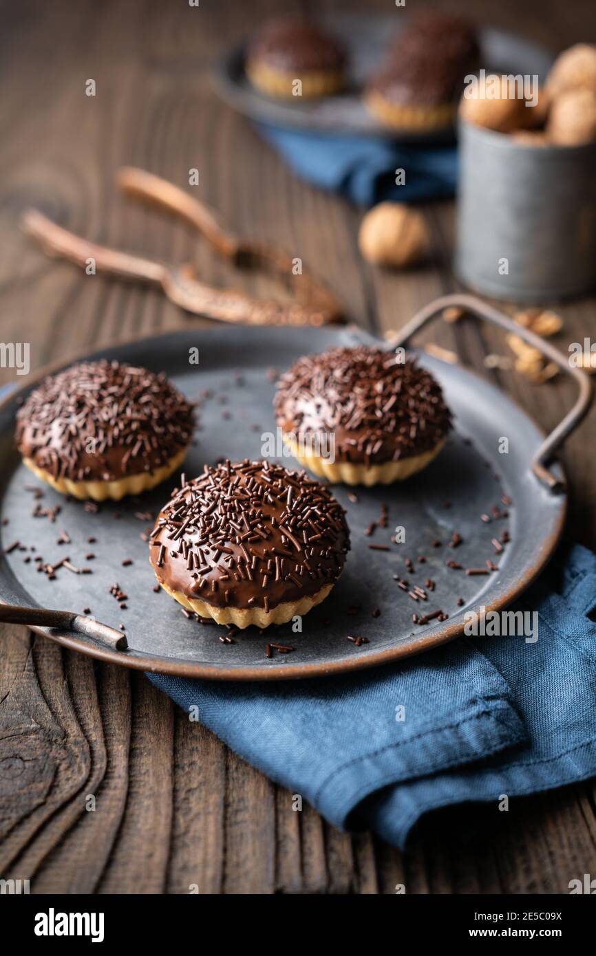 Frisch zubereitete süße Linzer Keksbecher mit Walnussfüllung, gekrönt mit Schokolade auf Holzhintergrund Stockfoto