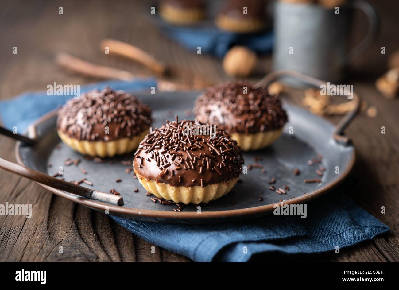 Frisch zubereitete süße Linzer Keksbecher mit Walnussfüllung, gekrönt mit Schokolade auf Holzhintergrund Stockfoto