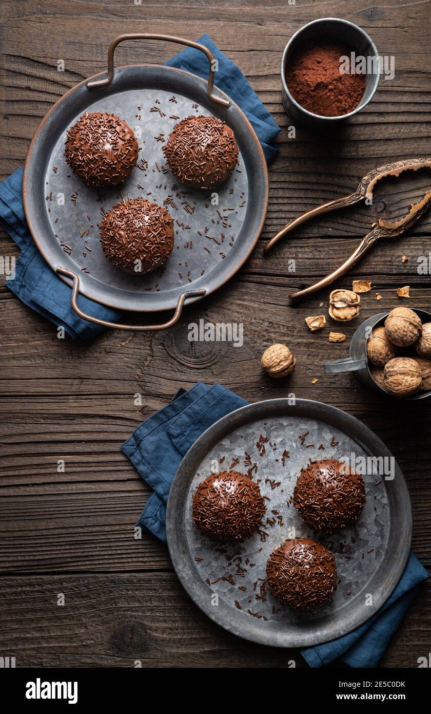 Frisch zubereitete süße Linzer Keksbecher mit Walnussfüllung, gekrönt mit Schokolade auf Holzhintergrund Stockfoto