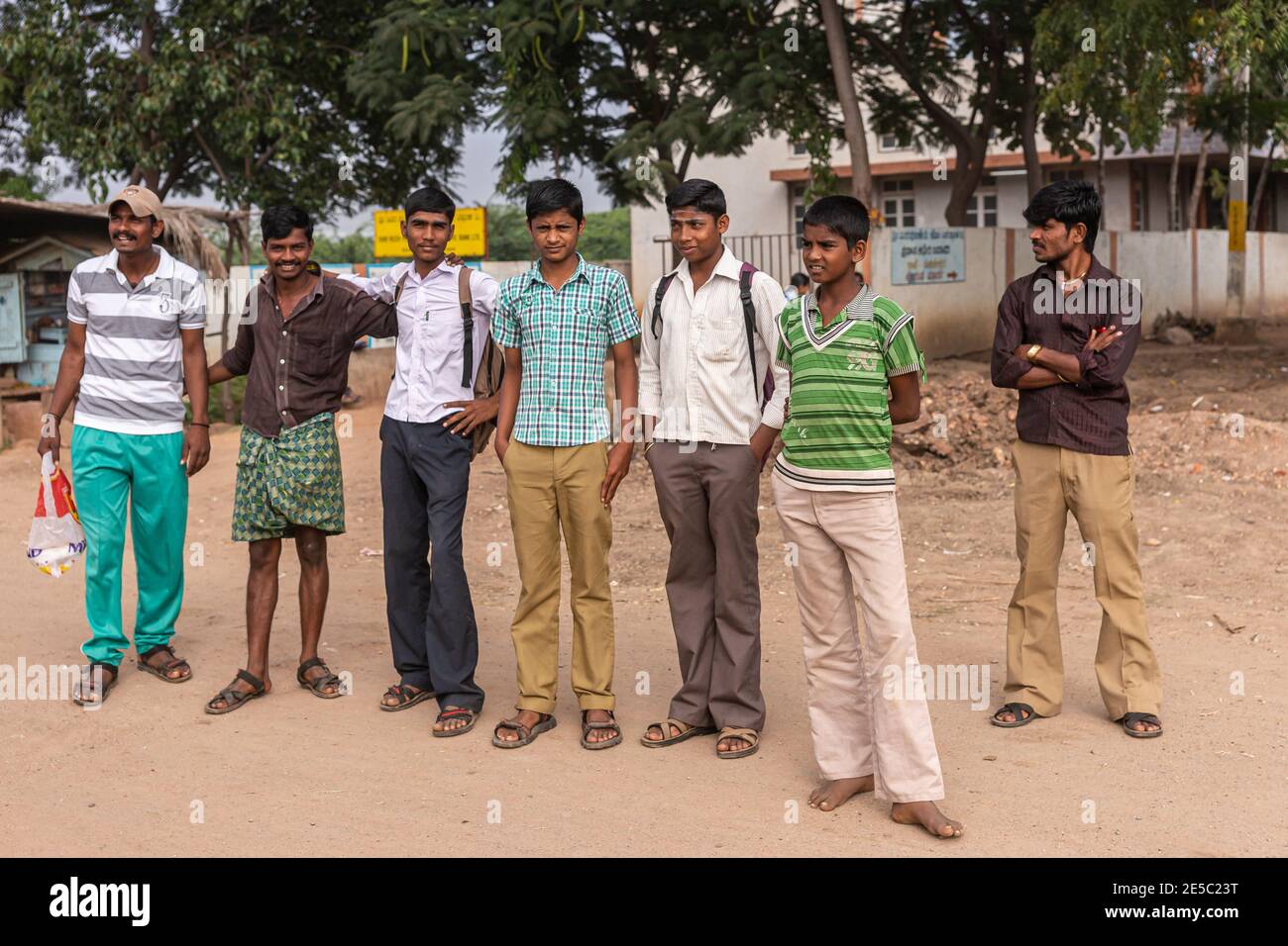 Nandakeshwar, Karnataka, Indien - 7. November 2013: Nahaufnahme einer Gruppe von männlichen Teenagern, die auf einer Schotterstraße standen und auf einen öffentlichen Bus warteten, der zur Schule gehen sollte. Stockfoto
