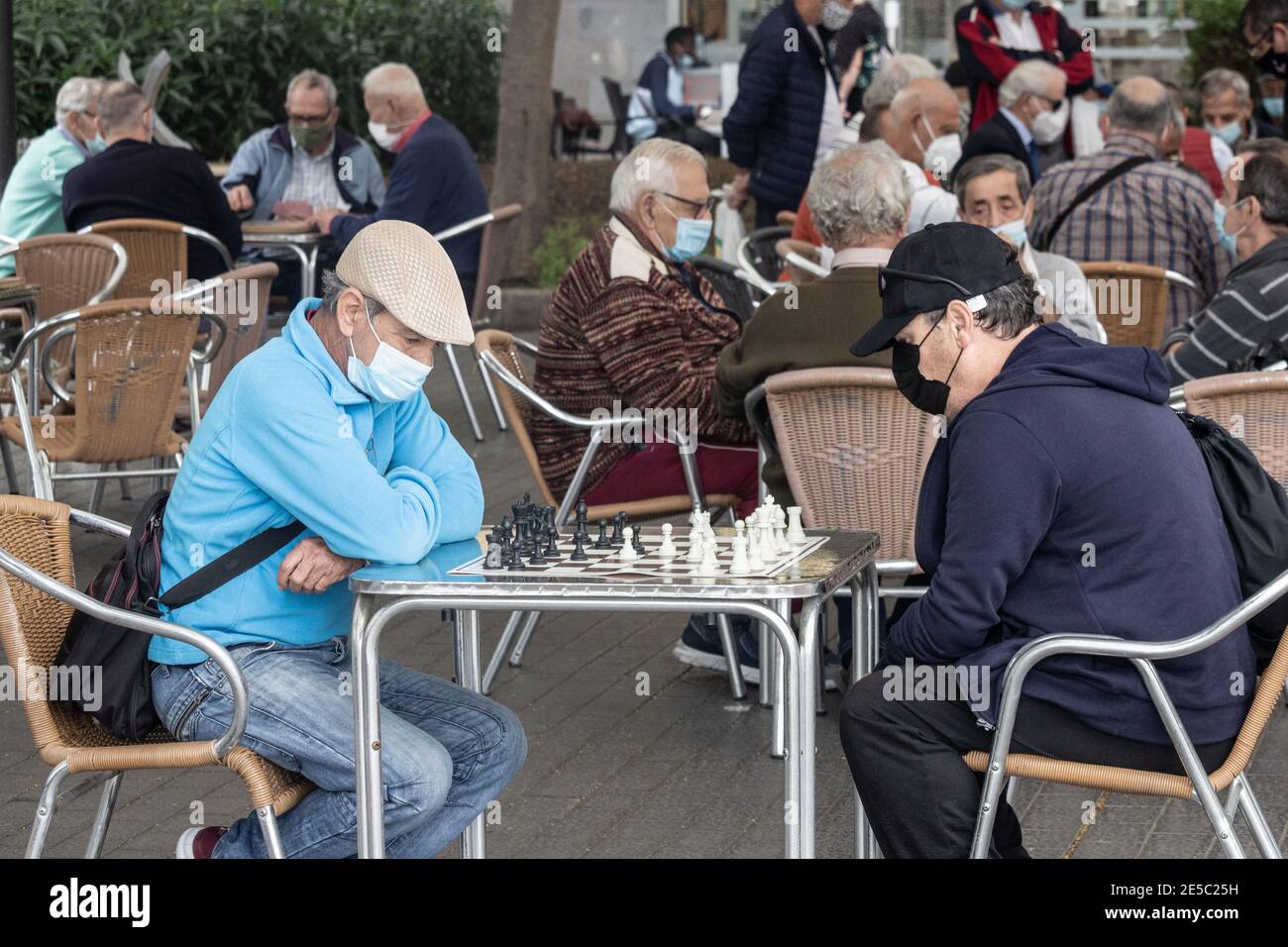 Spanische Männer mit Gesichtsmasken spielen Schach im Park in Spanien während Coronavirus, Covid 19 Pandemie Stockfoto