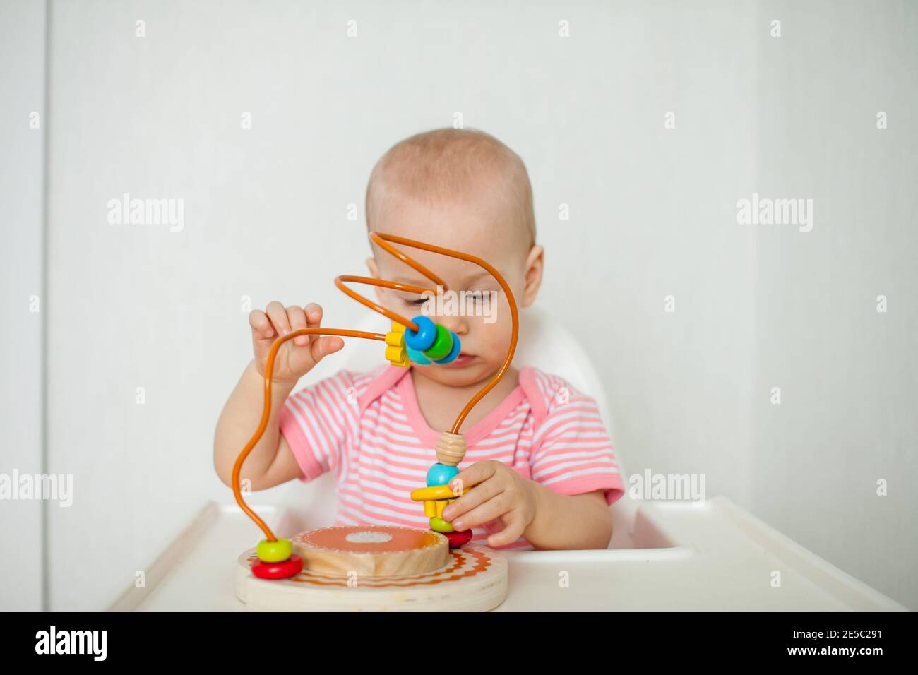 Kleines Mädchen spielt mit einem pädagogischen Labyrinth Spielzeug. Entwicklung von Feinmotorik und logischem Denken Stockfoto