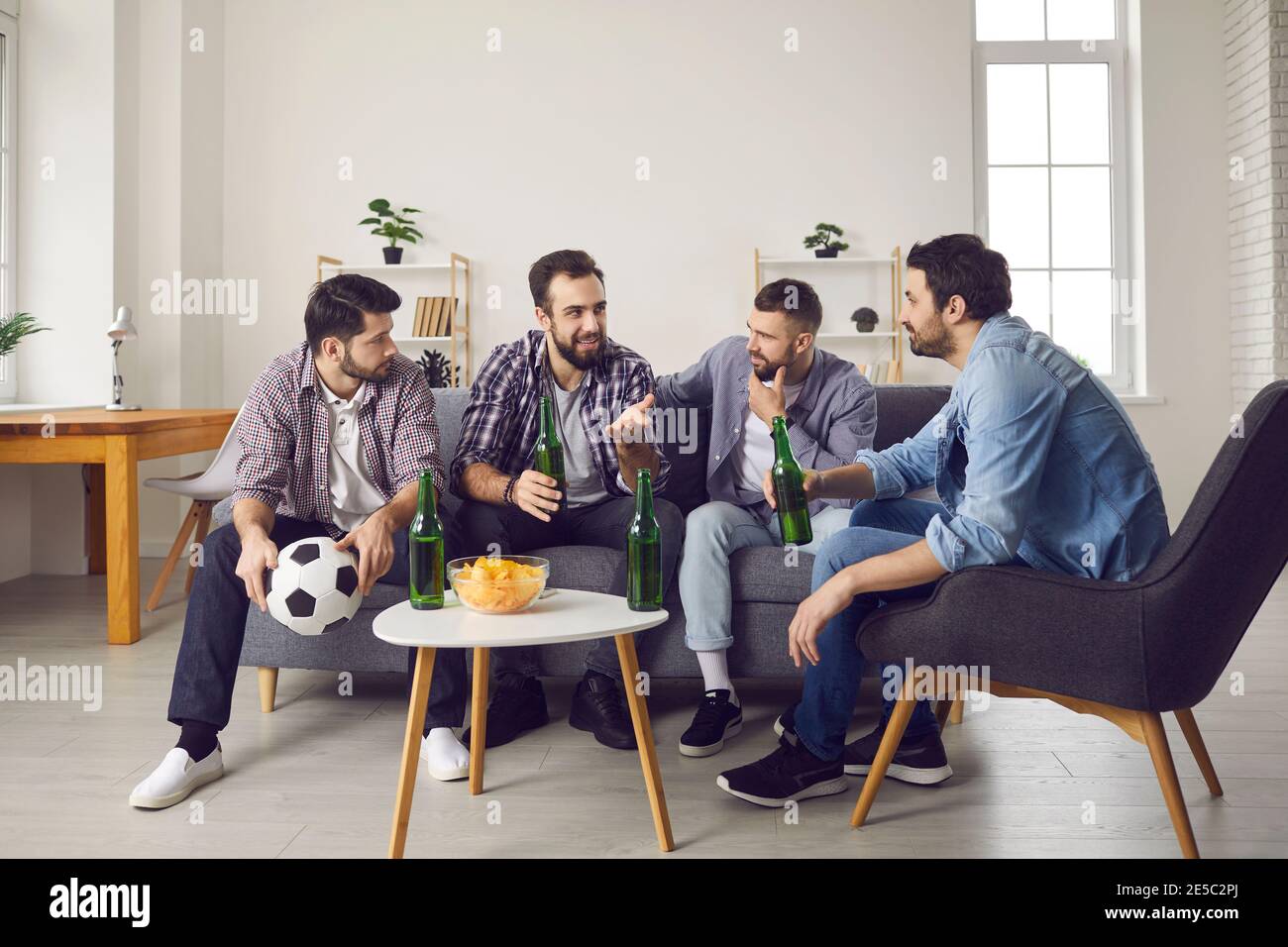 Gruppe von Männern auf dem Sofa sitzen, Bier trinken, Snacks essen und diskutieren Fußballspiel Stockfoto