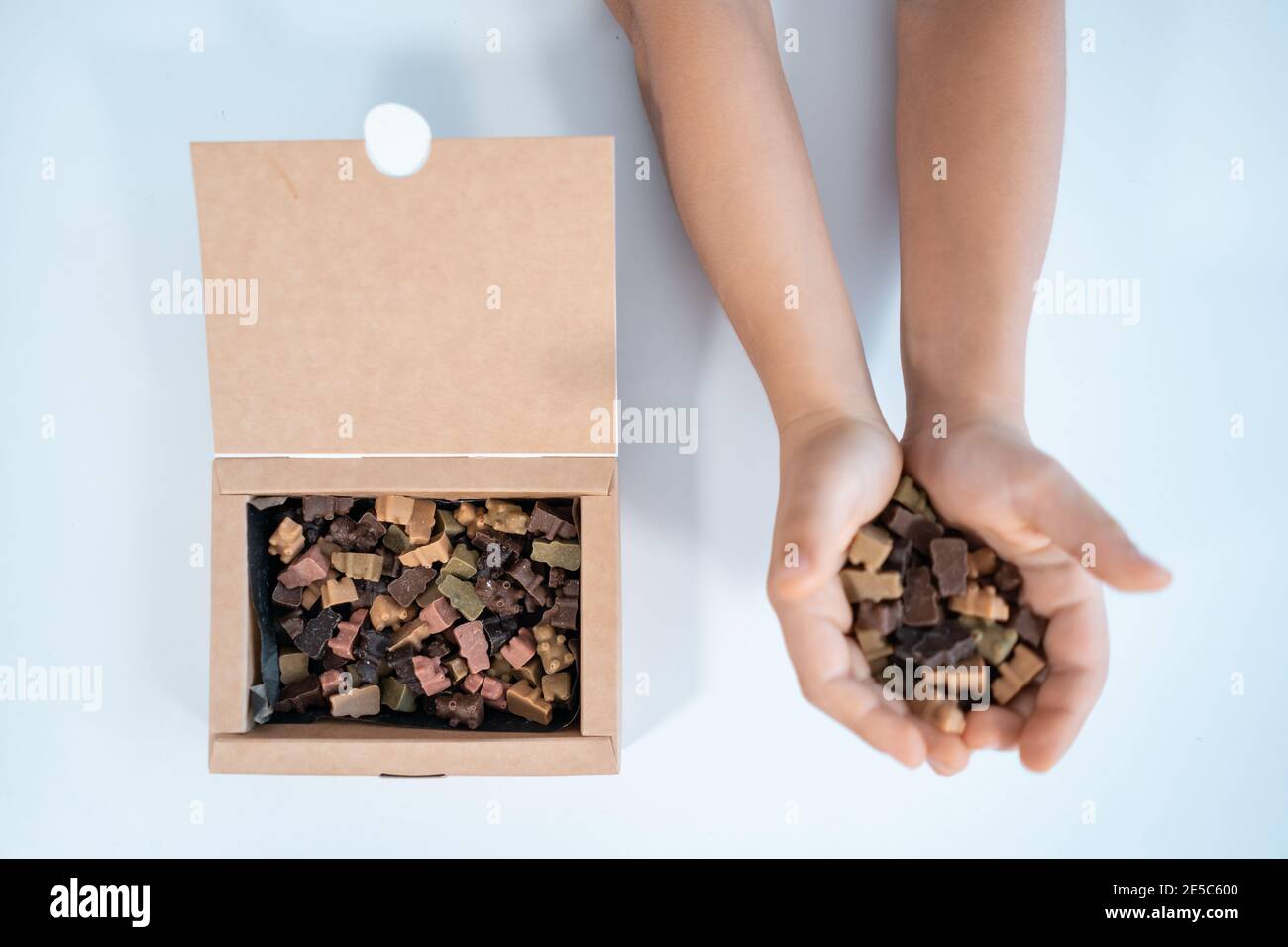 Draufsicht der Hände Nehmen Sie hausgemachte Süßigkeiten oder Schokolade Bonbons Aus Papierkarton Stockfoto