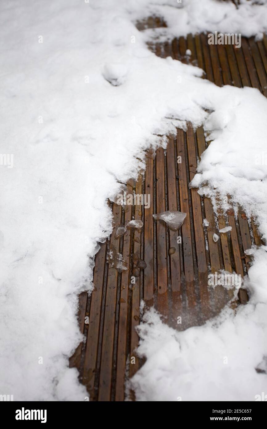 Schmelzender Schnee auf Dielen Stockfoto