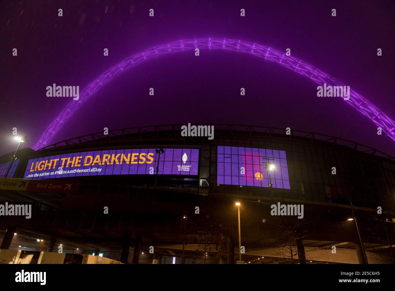 London, Großbritannien. 27. Januar 2021. Bei starkem Regen werden das Wembley-Stadion und sein Bogen am Holocaust-Gedenktag, einem Tag, der den Völkermord an sechs Millionen Juden und anderen Minderheiten während des Zweiten Weltkriegs durch die Nazis markiert, in Purpur beleuchtet. 25 ikonische britische Wahrzeichen wurden nach dem diesjährigen Thema „Be the Light in the Darkness“ beleuchtet. Aufgrund der Covid-19-Pandemie wird eine Zeremonie zur Erinnerung an die Opfer online stattfinden, die von Boris Johnson, Premierminister, und seiner Königlichen Hoheit Prinz von Wales unterstützt wird. Kredit: Stephen Chung / Alamy Live Nachrichten Stockfoto