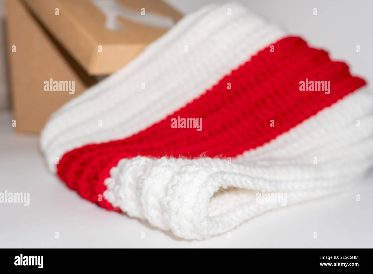 Strickschal weiß rot weiß ordentlich gefaltet neben Handwerk Feld auf weißem Hintergrund Nahaufnahme Stockfoto