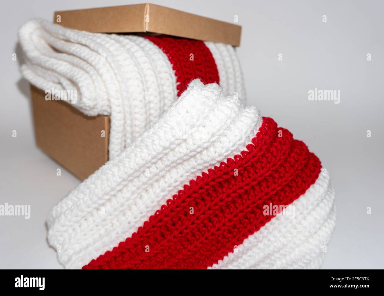 Weiß-rot-weiß gestrickter Schal in Pappkarton auf weißem Hintergrund Stockfoto