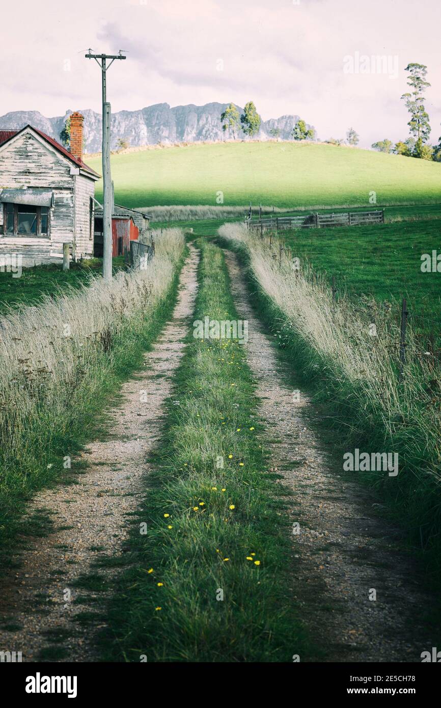 Bauernhaus am Mount Roland mit einer abgenutzten Straße, die vorbei führt Stockfoto