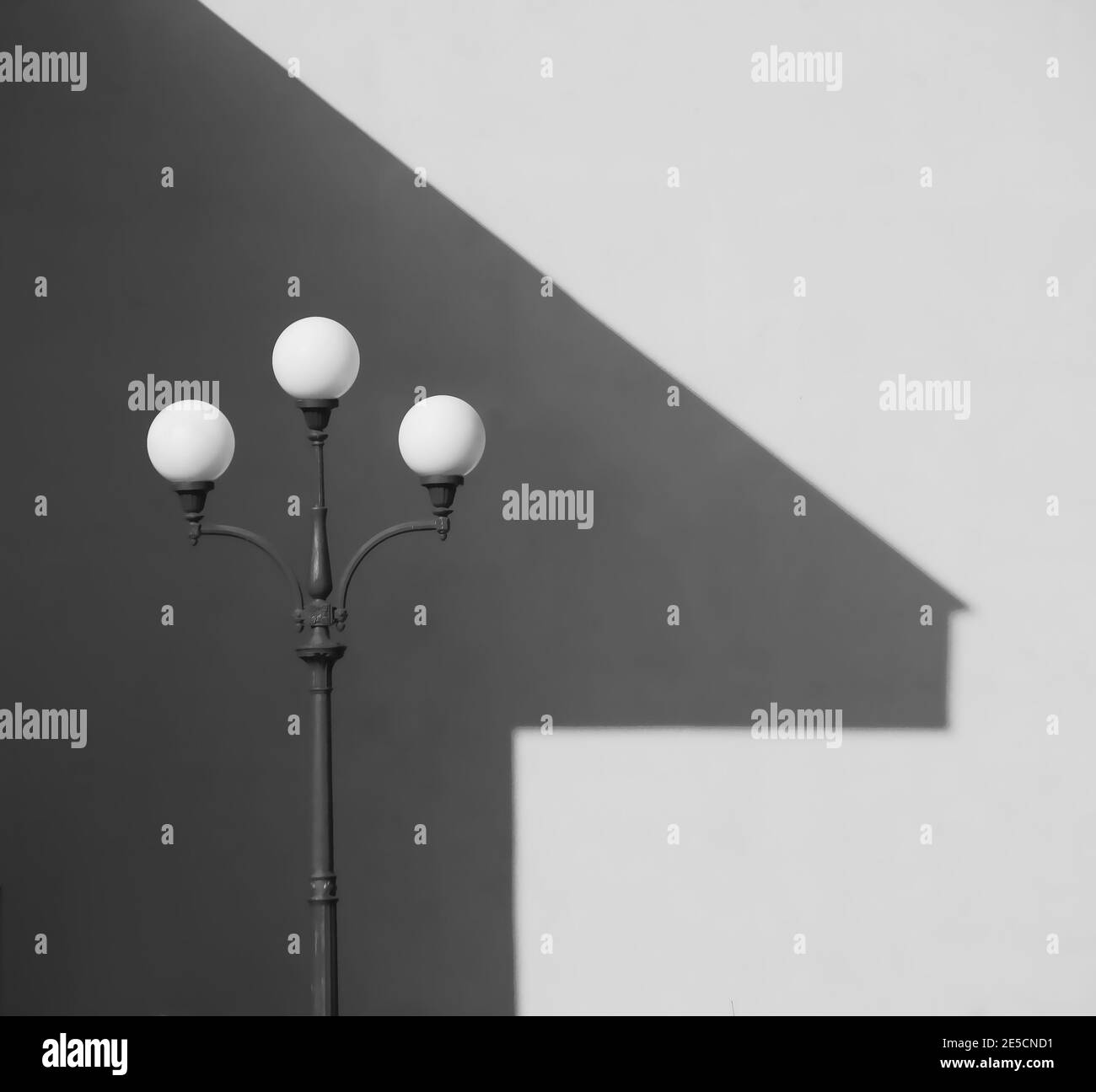 Abstrakter monochromer Hintergrund mit Straßenlaterne und Schatten des Hauses An der Wand Stockfoto