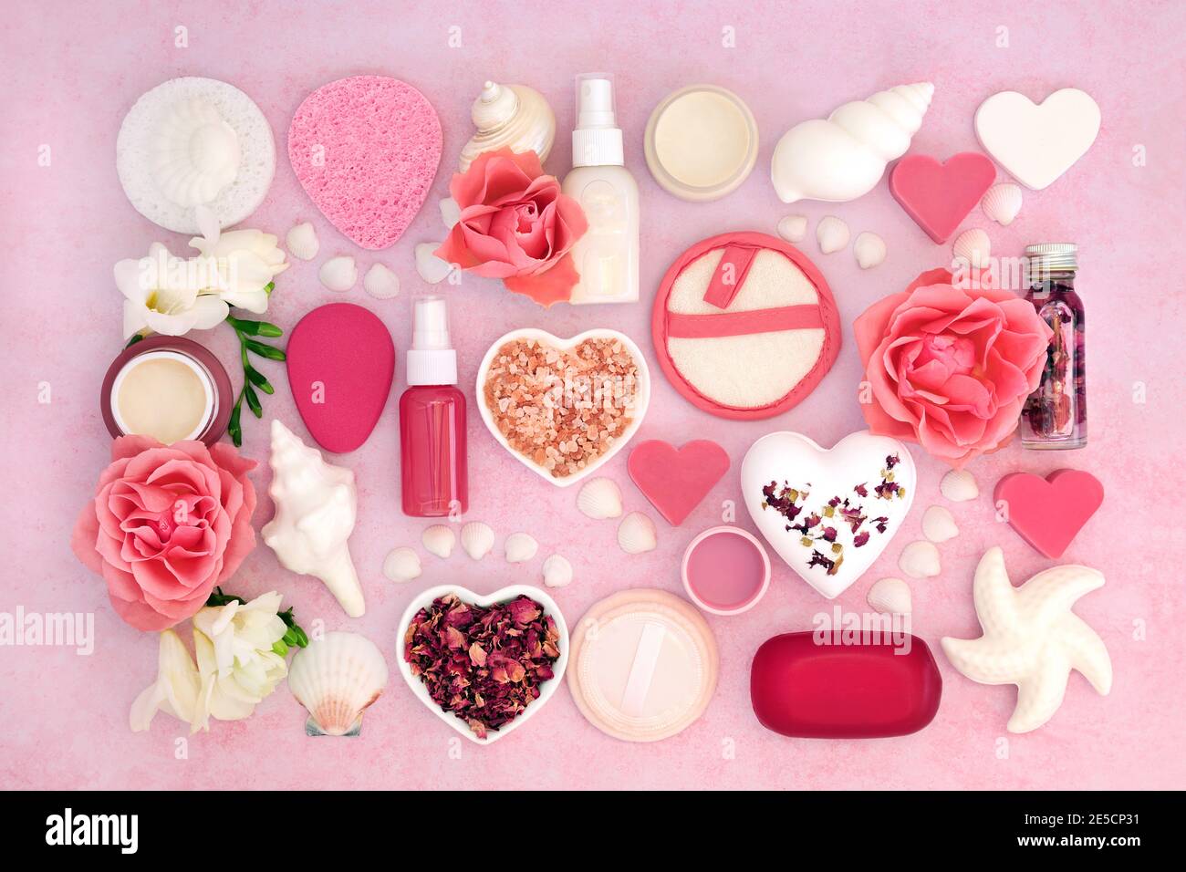 Beauty-Spa-Behandlungsprodukte für die Hautpflege & Körperpflege mit Rose & Freesia Blumen bilden einen abstrakten Hintergrund. Draufsicht auf meliertes Pink. Stockfoto