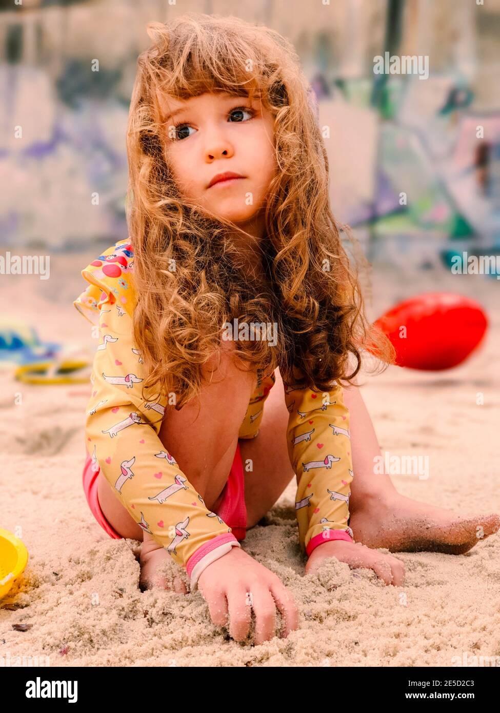 Porträt eines Mädchens am Strand sitzend und mit Sand spielend, Rio de