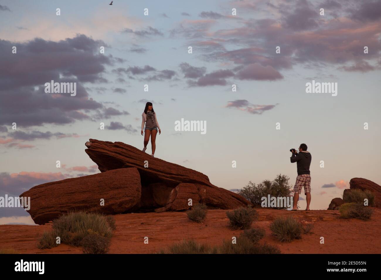 Horseshoe Bend, Arizona / USA - 25. Oktober 2014: Ein Mann fotografiert eine Frau, die auf einer orangenen Sandsteinformation steht und nach dem Tod verblasst Stockfoto