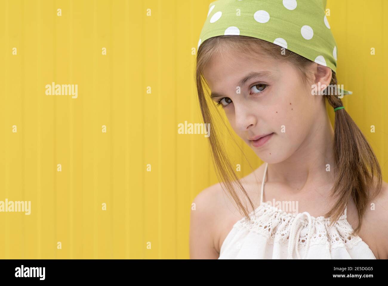 Porträt eines Mädchens mit einem grünen Kopftuch mit Punktmuster Stockfoto