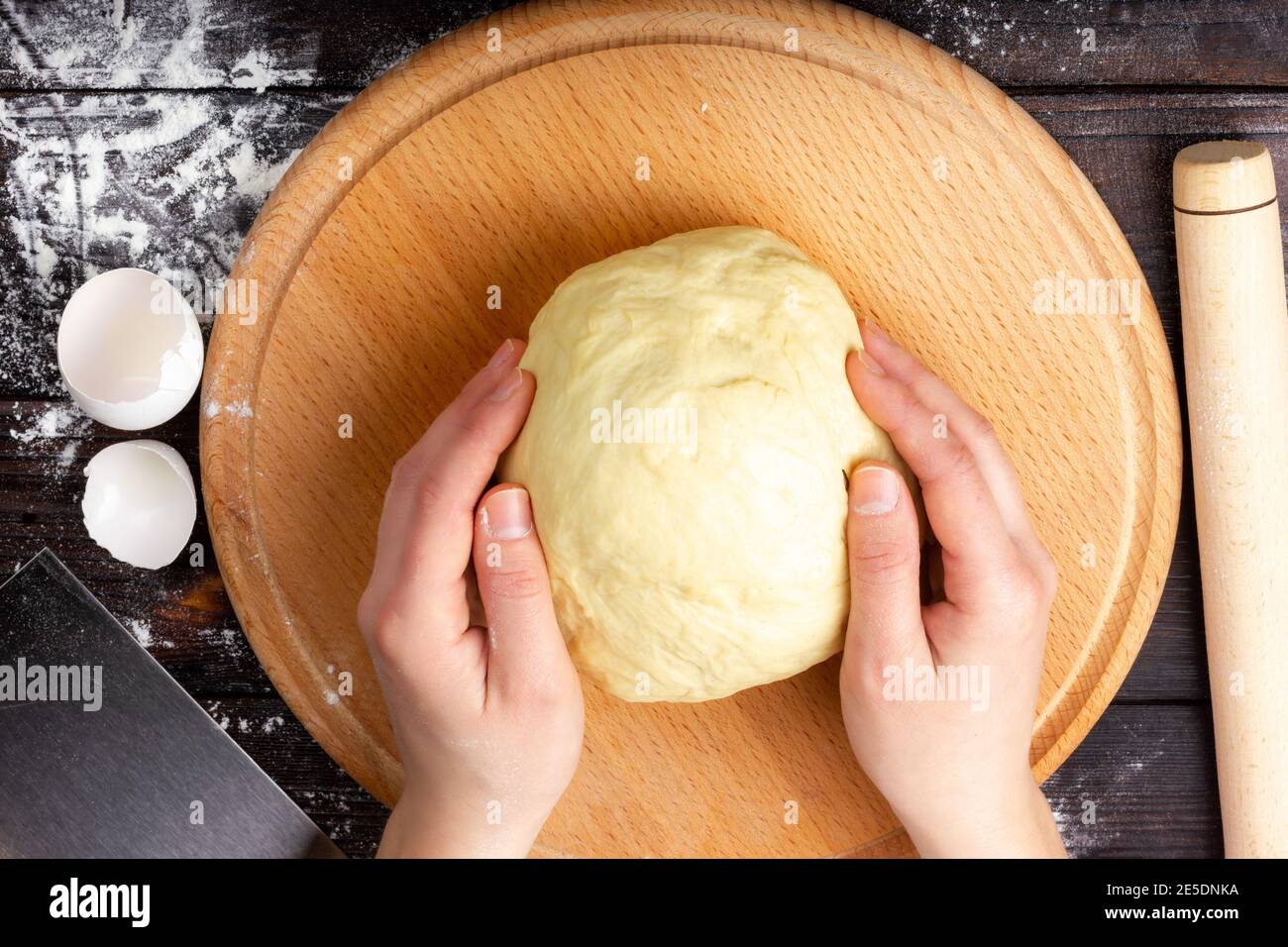 Der Prozess der Herstellung von Brotteig. Weibliche Hände halten den Teig. Der Teig steht auf dem Tisch. Flach Liegend. Stockfoto