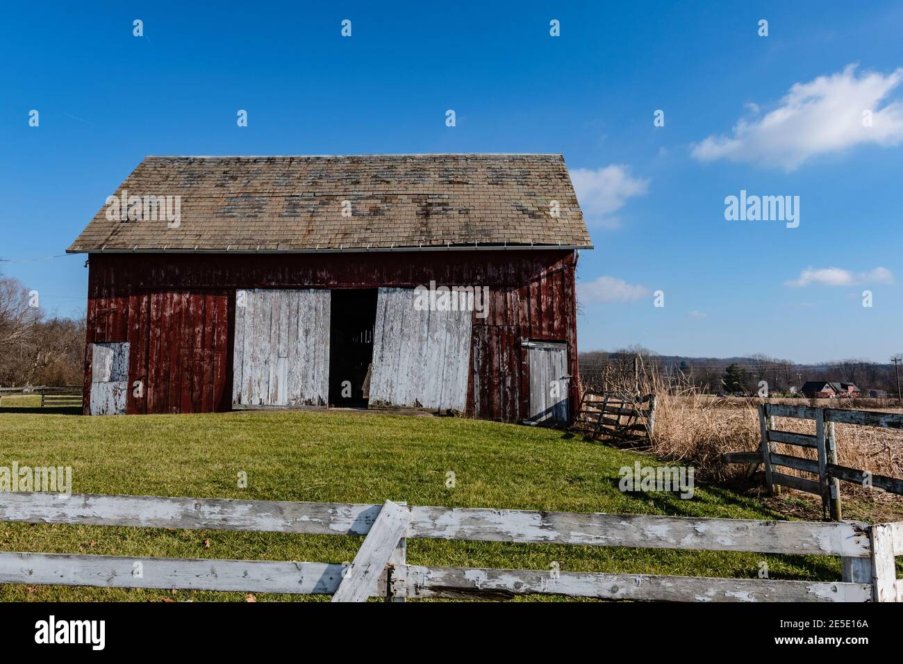 Alte verwitterte rote Scheune mit weißen Türen in einem ländlichen Querformat Stockfoto