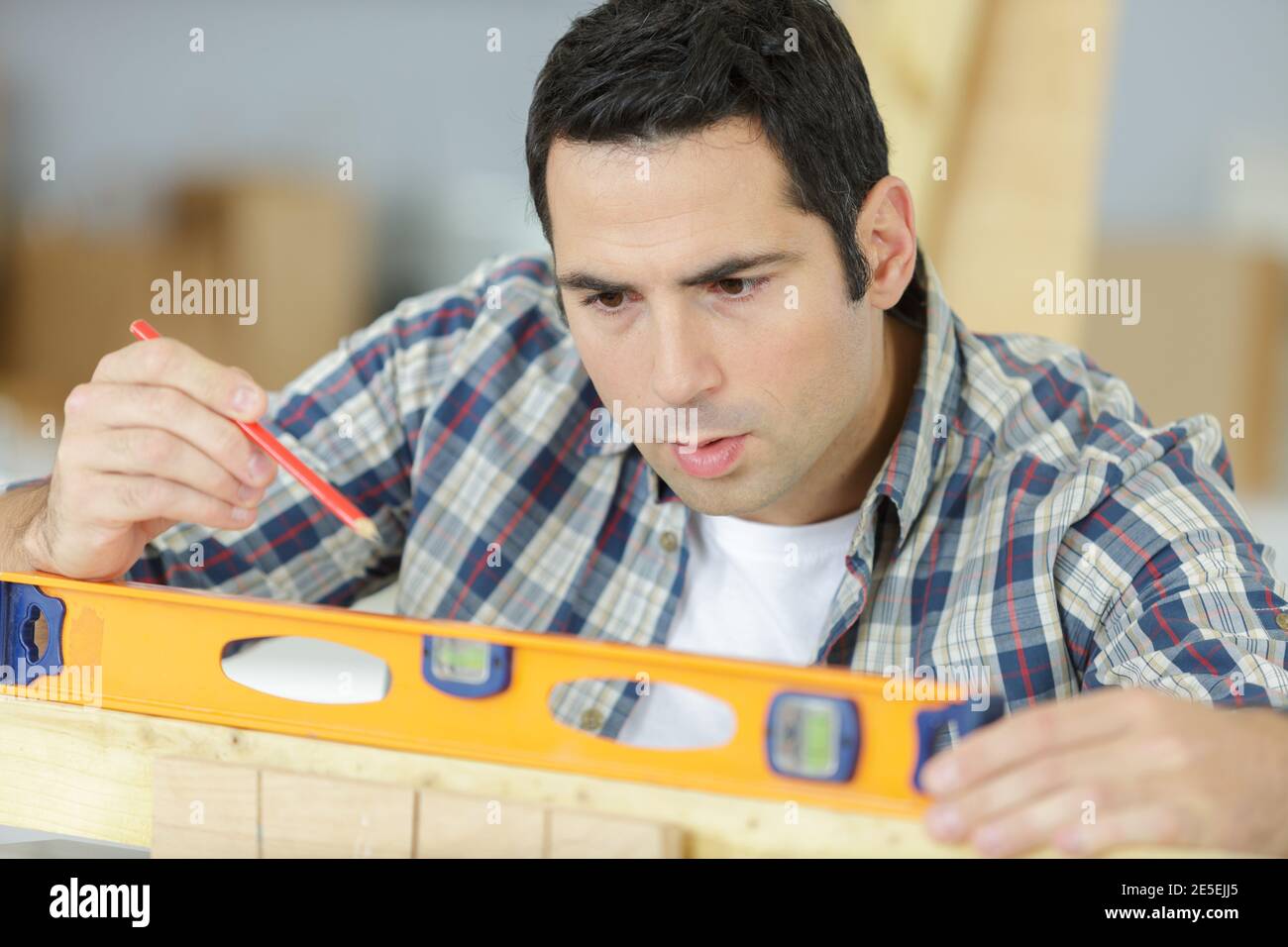 Nahaufnahme von männlichen Tischlern mit Ebene auf Holzbrett Stockfoto