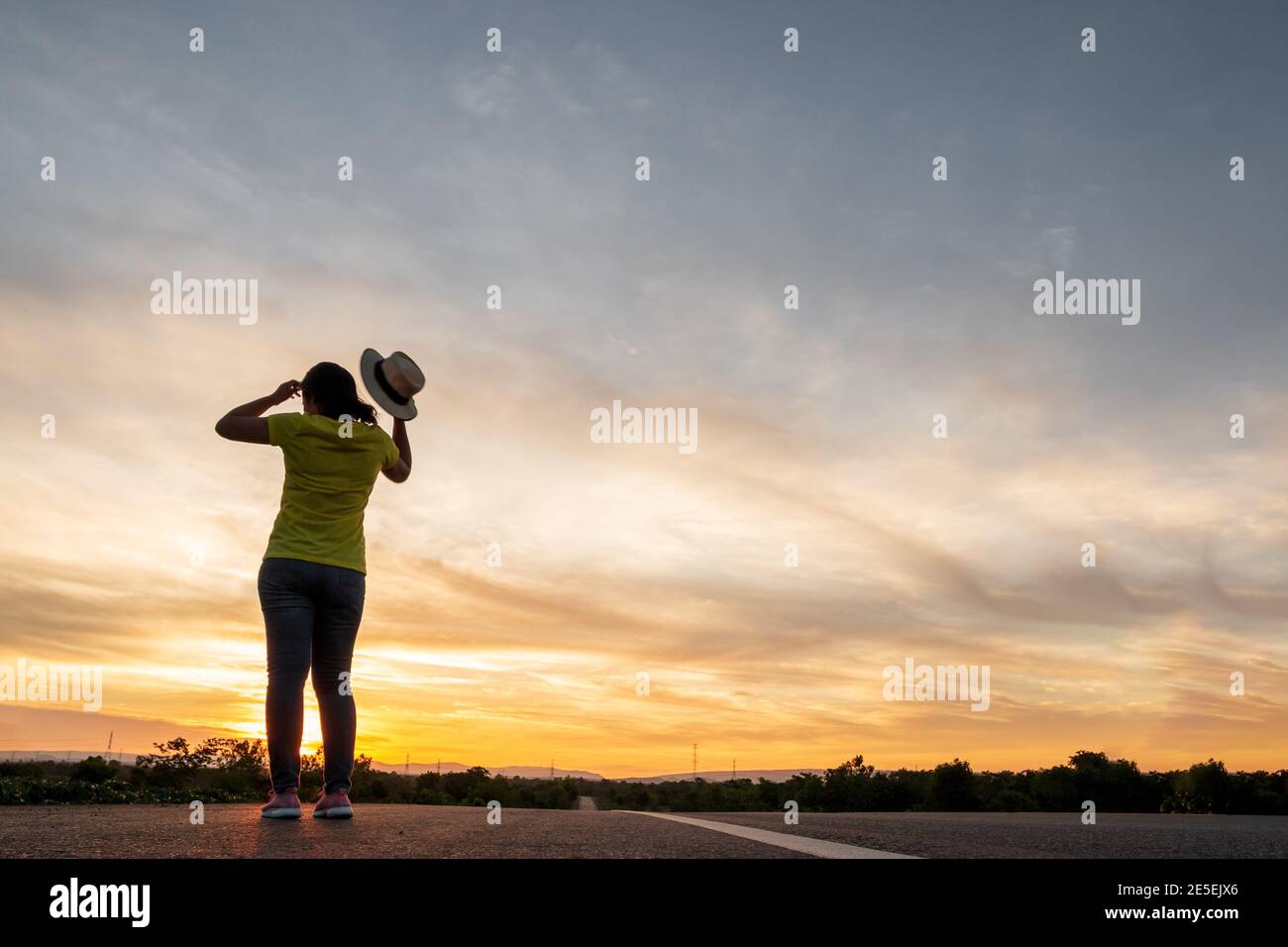 Frauen tragen T-Shirts, Jeans, Turnschuhe und Hüte bei Sonnenuntergang, stehen entlang der Autobahn zu reisen, Happy Mood, Urlaub Konzept Stockfoto