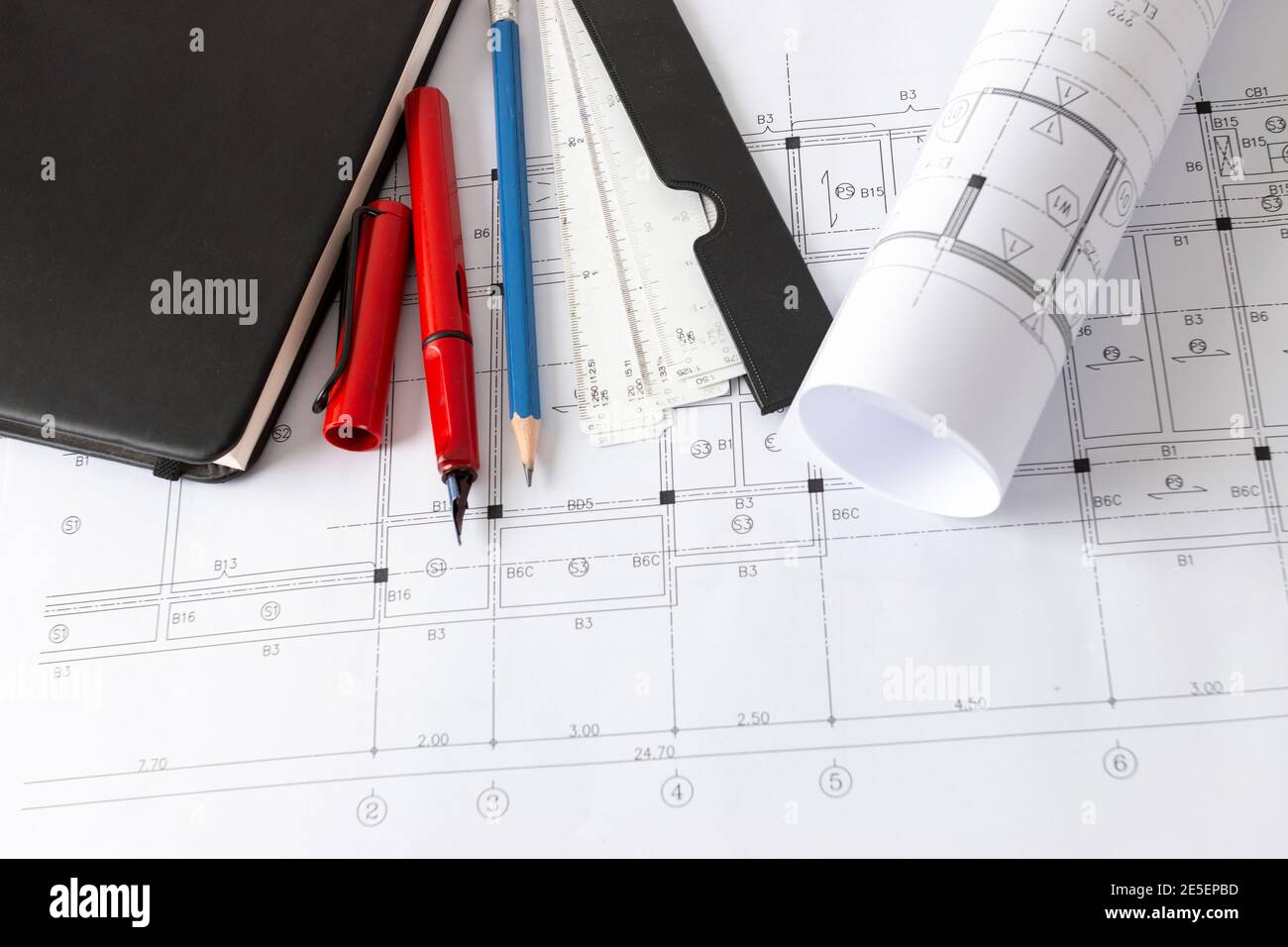 Rollen von Architekturentwürfen und Hausplänen auf dem Tisch und Architekten Zeichenwerkzeuge. Stockfoto