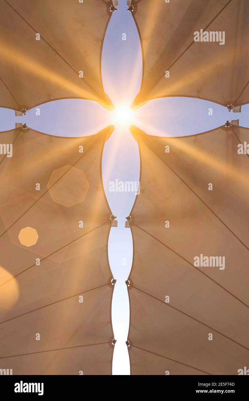 Lücken zwischen Schirmen bilden ein Kreuz mit dem blauen Himmel und der Sonne zeigt, mit Sonnenstern Stockfoto