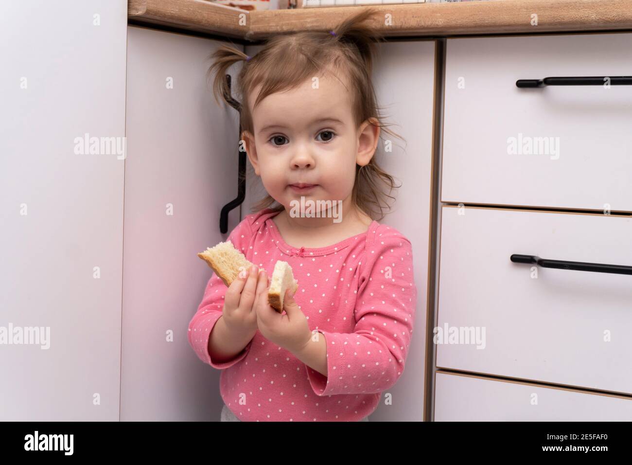 Niedlich liebenswert kaukasischen Baby Mädchen essen lecker leckeres Brot Stockfoto