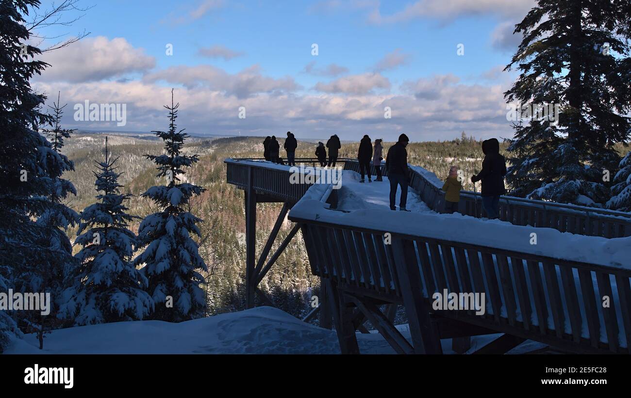 Menschen genießen die schöne Aussicht über die schneebedeckten Schwarzwaldberge von der Aussichtsplattform Ellbachseeblick in der Wintersaison an sonnigen Tagen. Stockfoto