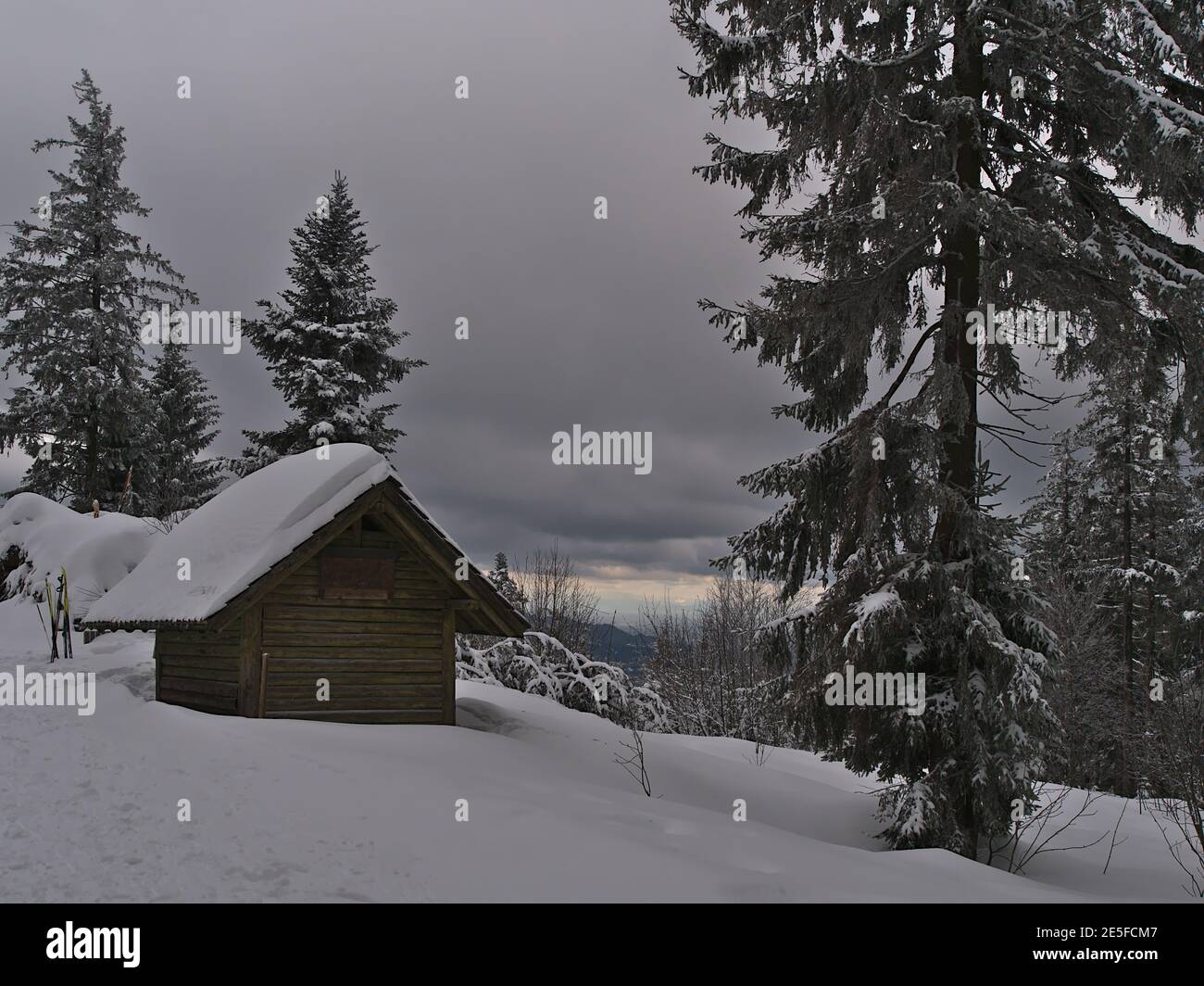 Friedliche Winterlandschaft mit hölzernen verschneiten Schuppen im Niedergebirge Schwarzwald am bewölkten Tag mit gefrorenen Bäumen. Stockfoto
