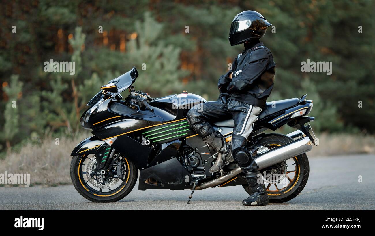 Biker in einem Helm und Leder Schutzausrüstung sitzt auf einem Motorrad, ein sportliches schnelles Motorrad Stockfoto